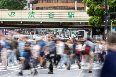 Tokyo, Japonya - 12 Mayıs 2024: İnsanlar Shibuya, Tokyo 'da işlek kavşağı geçiyor. Burası dünyanın en işlek kavşaklarından biri. (kasıtlı olarak insanların hareketlerini göstermek için bulanık)