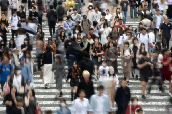 Tokyo, Japonya - 12 Mayıs 2024: İnsanlar Shibuya, Tokyo 'da işlek kavşağı geçiyor. Burası dünyanın en işlek kavşaklarından biri. (kasıtlı olarak insanların hareketlerini göstermek için bulanık)