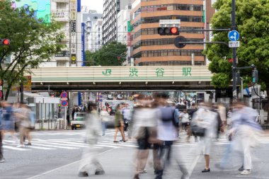 Tokyo, Japonya - 12 Mayıs 2024: İnsanlar Shibuya, Tokyo 'da işlek kavşağı geçiyor. Burası dünyanın en işlek kavşaklarından biri. (kasıtlı olarak insanların hareketlerini göstermek için bulanık)