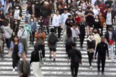 Tokyo, Japonya - 12 Mayıs 2024: İnsanlar Shibuya, Tokyo 'da işlek kavşağı geçiyor. Burası dünyanın en işlek kavşaklarından biri. (kasıtlı olarak insanların hareketlerini göstermek için bulanık)