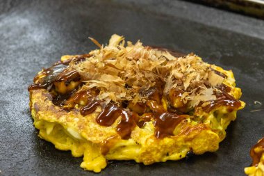 Okonomiyaki sıcak tavada yemek pişirir. Tereyağı ve lahanadan oluşan popüler bir kızartma tabağıdır.