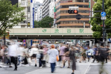 Tokyo, Japonya - 12 Mayıs 2024: İnsanlar Shibuya, Tokyo 'da işlek kavşağı geçiyor. Burası dünyanın en işlek kavşaklarından biri. (kasıtlı olarak insanların hareketlerini göstermek için bulanık)