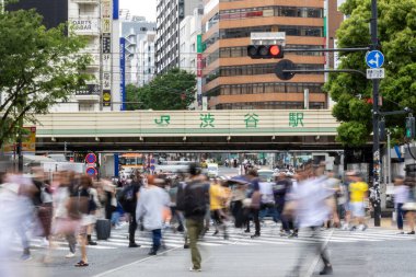 Tokyo, Japonya - 12 Mayıs 2024: İnsanlar Shibuya, Tokyo 'da işlek kavşağı geçiyor. Burası dünyanın en işlek kavşaklarından biri. (kasıtlı olarak insanların hareketlerini göstermek için bulanık)