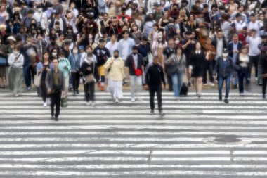 Tokyo, Japonya - 12 Mayıs 2024: İnsanlar Shibuya, Tokyo 'da işlek kavşağı geçiyor. Burası dünyanın en işlek kavşaklarından biri. (kasıtlı olarak insanların hareketlerini göstermek için bulanık)