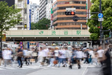 Tokyo, Japonya - 12 Mayıs 2024: İnsanlar Shibuya, Tokyo 'da işlek kavşağı geçiyor. Burası dünyanın en işlek kavşaklarından biri. (kasıtlı olarak insanların hareketlerini göstermek için bulanık)