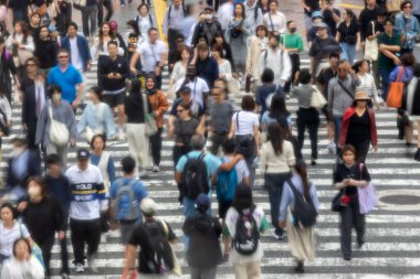 Tokyo, Japonya - 12 Mayıs 2024: İnsanlar Shibuya, Tokyo 'da işlek kavşağı geçiyor. Burası dünyanın en işlek kavşaklarından biri. (kasıtlı olarak insanların hareketlerini göstermek için bulanık)