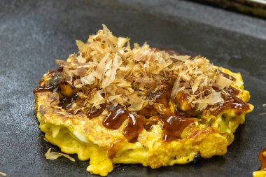 Okonomiyaki sıcak tavada yemek pişirir. Tereyağı ve lahanadan oluşan popüler bir kızartma tabağıdır.