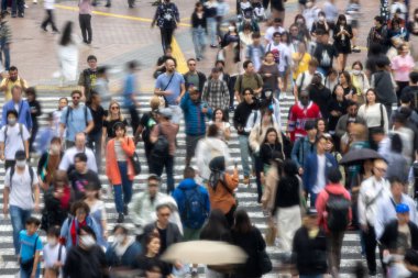 Tokyo, Japonya - 12 Mayıs 2024: İnsanlar Shibuya, Tokyo 'da işlek kavşağı geçiyor. Burası dünyanın en işlek kavşaklarından biri. (kasıtlı olarak insanların hareketlerini göstermek için bulanık)