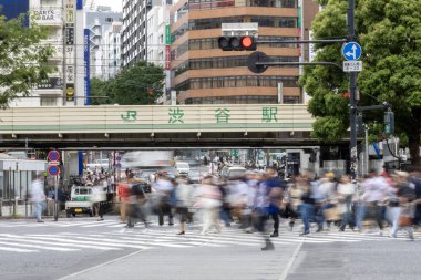 Tokyo, Japonya - 12 Mayıs 2024: İnsanlar Shibuya, Tokyo 'da işlek kavşağı geçiyor. Burası dünyanın en işlek kavşaklarından biri. (kasıtlı olarak insanların hareketlerini göstermek için bulanık)
