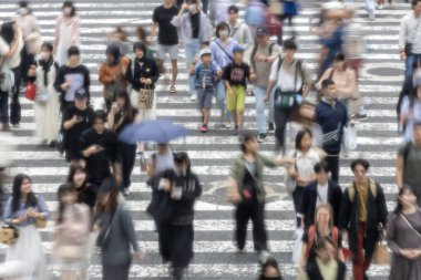 Tokyo, Japonya - 12 Mayıs 2024: İnsanlar Shibuya, Tokyo 'da işlek kavşağı geçiyor. Burası dünyanın en işlek kavşaklarından biri. (kasıtlı olarak insanların hareketlerini göstermek için bulanık)