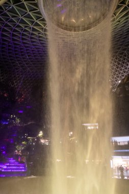 Singapur - 5 Haziran 2024: Jewel Singapur Changi Havalimanı 'ndaki Yağmur Girdabı çeşmesinin gece vakti aydınlanması.
