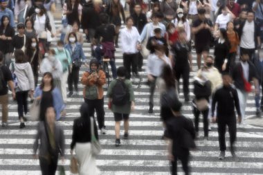 Tokyo, Japonya - 12 Mayıs 2024: İnsanlar Shibuya, Tokyo 'da işlek kavşağı geçiyor. Burası dünyanın en işlek kavşaklarından biri. (kasıtlı olarak insanların hareketlerini göstermek için bulanık)