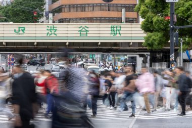 Tokyo, Japonya - 12 Mayıs 2024: İnsanlar Shibuya, Tokyo 'da işlek kavşağı geçiyor. Burası dünyanın en işlek kavşaklarından biri. (kasıtlı olarak insanların hareketlerini göstermek için bulanık)