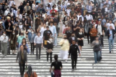 Tokyo, Japonya - 12 Mayıs 2024: İnsanlar Shibuya, Tokyo 'da işlek kavşağı geçiyor. Burası dünyanın en işlek kavşaklarından biri. (kasıtlı olarak insanların hareketlerini göstermek için bulanık)