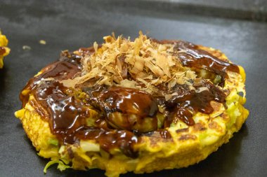 Okonomiyaki sıcak tavada yemek pişirir. Tereyağı ve lahanadan oluşan popüler bir kızartma tabağıdır.