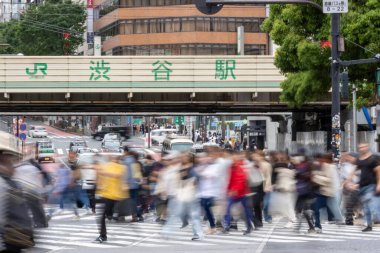 Tokyo, Japonya - 12 Mayıs 2024: İnsanlar Shibuya, Tokyo 'da işlek kavşağı geçiyor. Burası dünyanın en işlek kavşaklarından biri. (kasıtlı olarak insanların hareketlerini göstermek için bulanık)