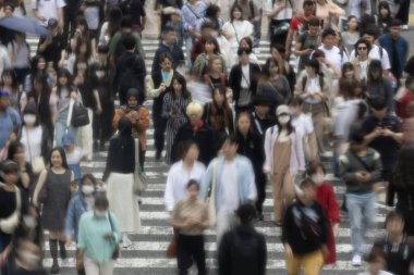 Tokyo, Japonya - 12 Mayıs 2024: İnsanlar Shibuya, Tokyo 'da işlek kavşağı geçiyor. Burası dünyanın en işlek kavşaklarından biri. (kasıtlı olarak insanların hareketlerini göstermek için bulanık)
