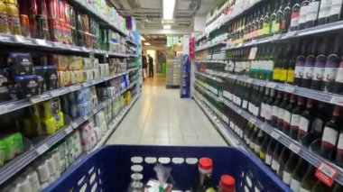 Singapur - 11 Ekim 2024: Süpermarketteki raflar arasında alışveriş arabası hareket ediyor