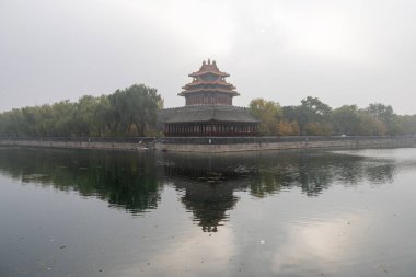 Beijing, China- 2 Nov 2024: Forbidden City Corner Tower, or Jiaolou tower and river in the misty day. It is a landmark in Beijing, China clipart