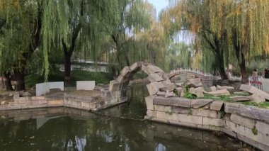 Pekin, Çin - 3 Kasım 2024: Çin, Pekin 'deki Yuanmingyuan Parkı içindeki harabe taş köprü. Yuanmingyuan 'da kalan tek taş köprü, derede daralan küçük bir kemer..