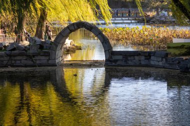 Pekin, Çin - 3 Kasım 2024: Çin, Pekin 'deki Yuanmingyuan Parkı içindeki harabe taş köprü. Yuanmingyuan 'da kalan tek taş köprü, derede daralan küçük bir kemer..