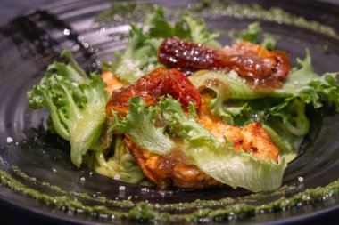 Izgara tavuklu makarna ve siyah tabakta fesleğen sosu.