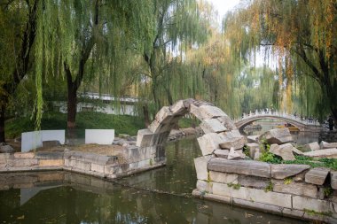 Pekin, Çin - 3 Kasım 2024: Çin, Pekin 'deki Yuanmingyuan Parkı içindeki harabe taş köprü. Yuanmingyuan 'da kalan tek taş köprü, derede daralan küçük bir kemer..