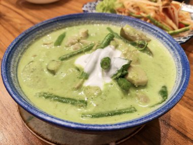 Arka plandaki kasede Tayland usulü yeşil körili tavuk..