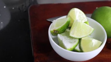 Kesme tahtasına yeşil limon dilimlenmiş.