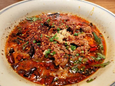 Sichuan usulü haşlanmış biftek. Yemek masasında acı biber yağında dilimlenmiş et, Çin yemeği.