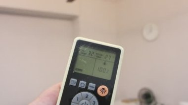 Beyaz tavan vantilatörünü açmak için uzaktan kumanda kullanıyor.