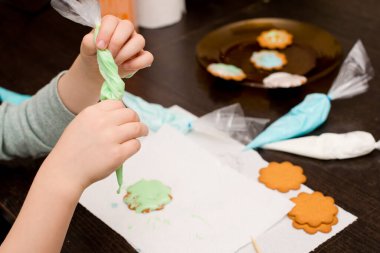 Baking holiday cookies. Child decorated Christmas cookies with sugar icing. Seasonal Christmas lifestyle at home with children. Helper of Santa.