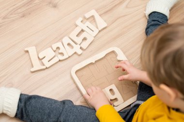 Bulmaca numaraları. Çocuk ahşap numaralarla oynuyor. Erken eğitim, sözlü ve hafıza oyunu.
