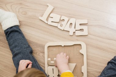 Bulmaca numaraları. Çocuk ahşap numaralarla oynuyor. Erken eğitim, sözlü ve hafıza oyunu.