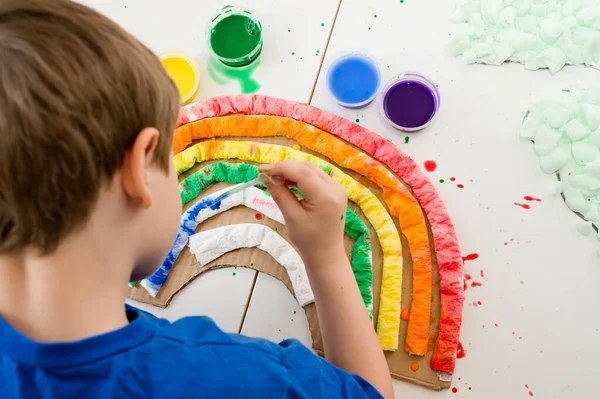 Kid at home makes and paints a rainbow. Exercise for Young artist. Early education, Montessori methodology. Implement to develop fine motoric skills. Zero waste, DIY games at home.