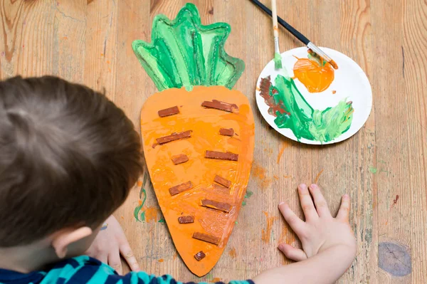 Second chance for packaging. Boy making a carrot from cardboard. Class for therapy of art. Fine motor skils, task of sensorics. Activities at home.
