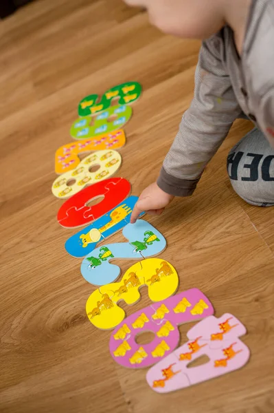 stock image Toddler playing with toy numbers on the floor. Intellectual math game, preschool implement for early education.