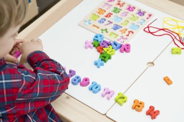 Çocuk oyun yoluyla numaraları öğreniyor. Tahta sayılar ve ayakkabı bağcıklarıyla duyusal aktivite. Evde eğitim, okul öncesi eğitim, Montessori metodolojisi. sayılar dizisi, aritmetik problemler.