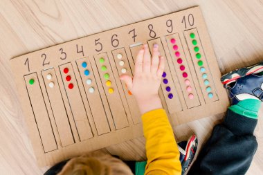 Pamuk yumaklarıyla kayışları numaralandırılmış oyuğa yerleştirin. Anaokulları için okul öncesi eğitim yardımı. Çocuklar erken yaşta zeka için montessori setini öğreniyorlar.