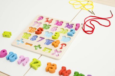 Çocuk oyun yoluyla numaraları öğreniyor. Tahta sayılar ve ayakkabı bağcıklarıyla duyusal aktivite. Evde eğitim, okul öncesi eğitim, Montessori metodolojisi. sayılar dizisi, aritmetik problemler.