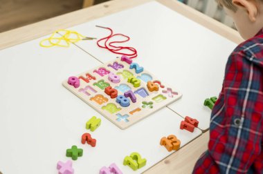 Çocuk oyun yoluyla numaraları öğreniyor. Tahta sayılar ve ayakkabı bağcıklarıyla duyusal aktivite. Evde eğitim, okul öncesi eğitim, Montessori metodolojisi. sayılar dizisi, aritmetik problemler.