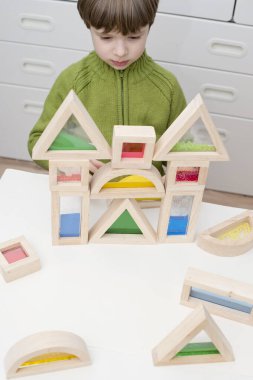 Çocuk kum, su, boncuk ve akrilikle dolu farklı şekil ve renk duyusal bloklarla oynuyor. Yaratıcılık, hayal gücünü geliştirme, inşaat, binalar, evler, kaleler oluşturma oyunu. 