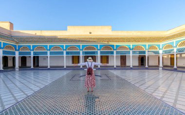 A young tourist with open arms looking at Courtyard at El Bahia Palace, Marrakech, Morocco