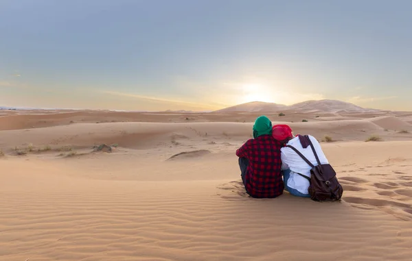 Desert Sunset. Romantic couple sitting  enjoying  the warm colors of desert during sunset.  Desert of morocco
