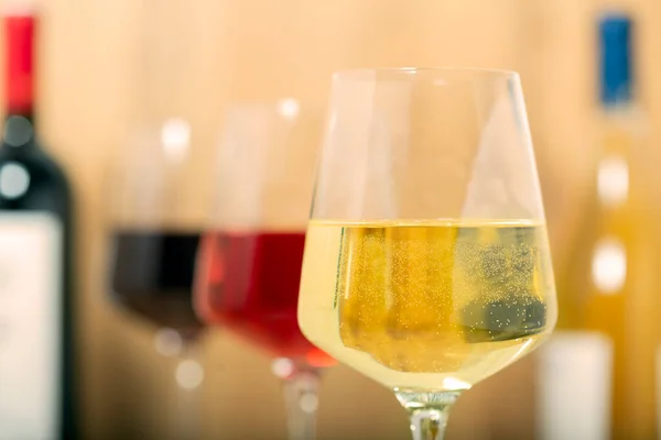素朴なセラーとワインバーでの試飲体験 バラのワインのガラスとバックグラウンドで高級ワインのコレクション — ストック写真
