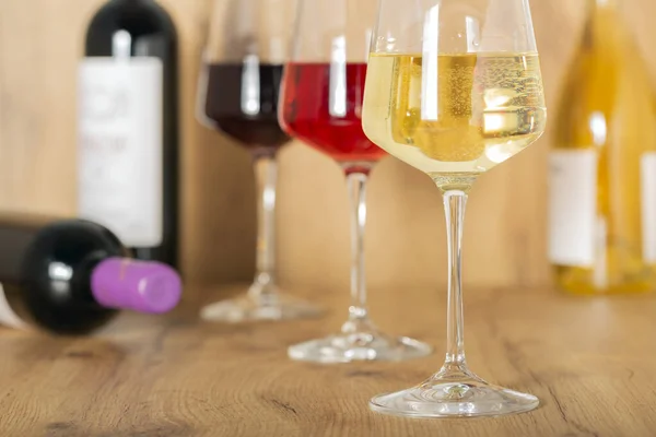 素朴なセラーとワインバーでの試飲体験 バラのワインのガラスとバックグラウンドで高級ワインのコレクション — ストック写真