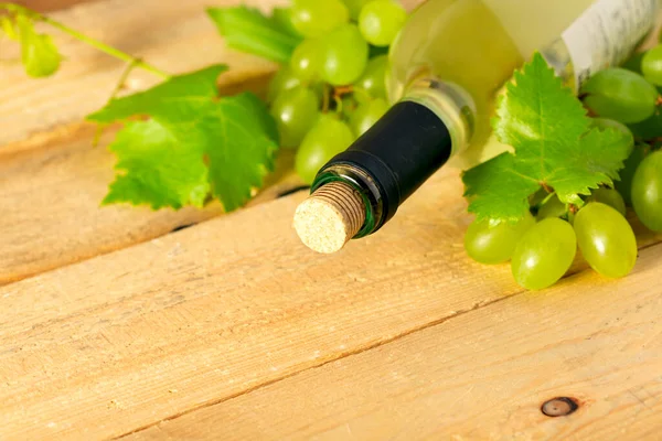 木製のテーブルの上に白ワイン ブドウと葉のボトル — ストック写真