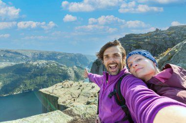 Bir çift kayanın üstünde selfie çekiyor ve Preikestolen 'ın manzarasına hayran. Havadan çekilmiş, çift için üst perspektif. Fiyordun sonsuz görünümü. 