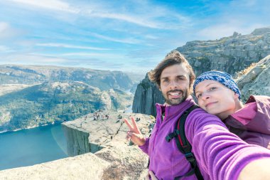 Bir çift kayanın üstünde selfie çekiyor ve Preikestolen 'ın manzarasına hayran. Havadan çekilmiş, çift için üst perspektif. Fiyordun sonsuz görünümü. 