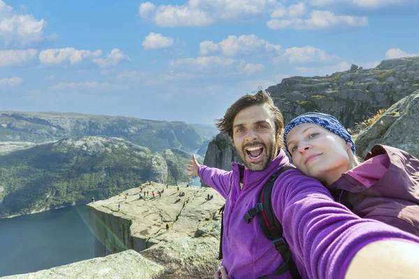 stock image Couple taking a selfie on a rock and admiring a view on Preikestolen. Aerial shot, upper perspective on the couple. Endless view of the fjord. 